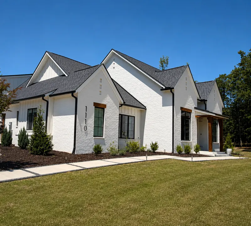 White painted brick exterior with dark roof, black gutters and cedar window headers