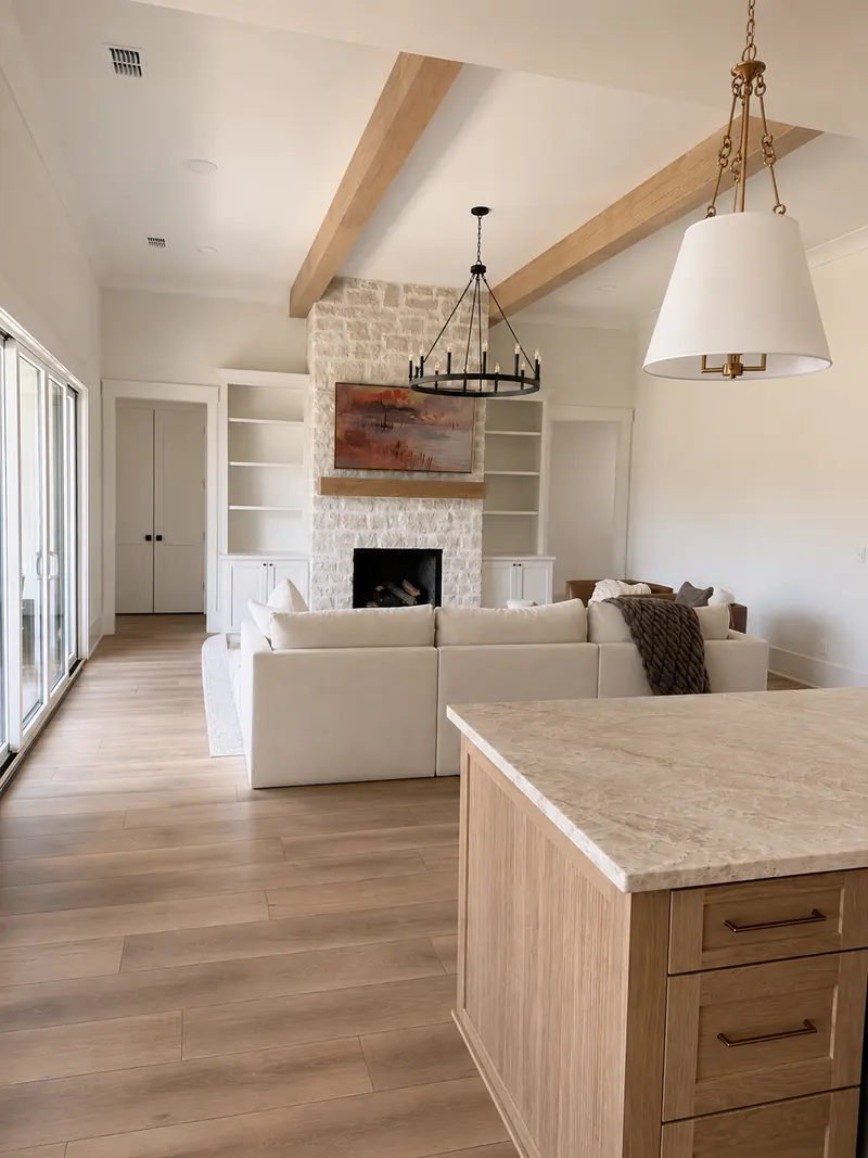 Living room with stone fireplace, built-in shelves and wood ceiling beams