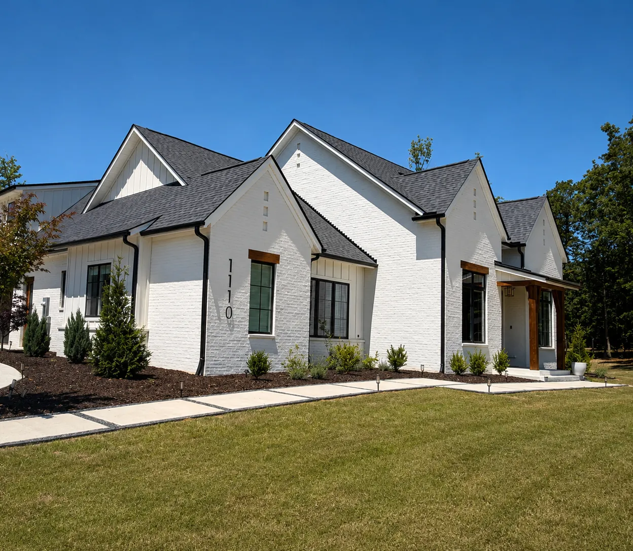 White painted brick home with dark roof and cedar accents